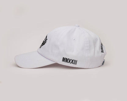 A white coloured, one-size-fits-all 6-panel cap, made of 100% cotton, On the left side of the cap, "MMXXIII" is neatly embroidered in black, signifying the year 2023 in Roman numerals. 